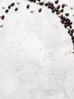 Top view of raw mixed beans on gray concrete background. Mixed of uncoocked black, red and white beans with copy space. Fodd background. Vegan protein concept.