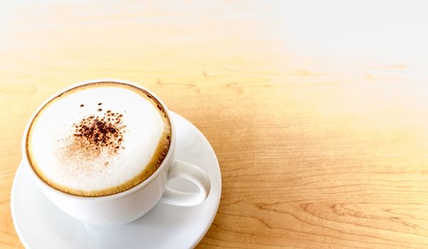 A cup of hot coffee cappuccino on wood table background