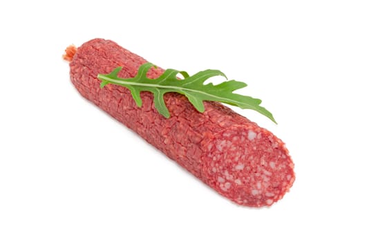 Partly cut salami and fresh leaf of the arugula on it on a light background
