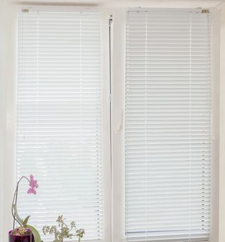 White Venetian blinds with manual control on the modern tilt and turn plastic window 
