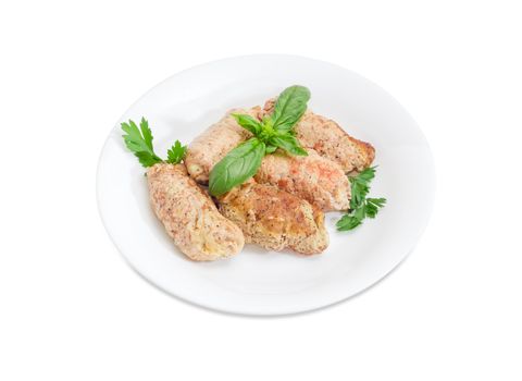 Braised meat roulades with filling from bread dried crusts and mushrooms decorated with basil and parsley twigs on a white dish on a white background
