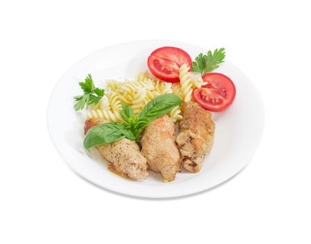 Braised meat roulades with filling from bread dried crusts and mushrooms and beside spiral pasta and tomato, decorated with basil and parsley twigs on a white dish on a white background
