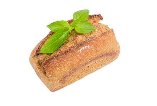 Small whole of the wheat sourdough bread decorated with basil twig on a white background
