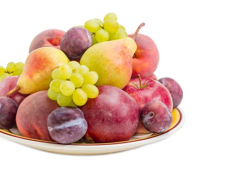 Fragment of the big yellow dish with several apples, pears, plums, peaches and clusters of white grapes closeup on a white background
