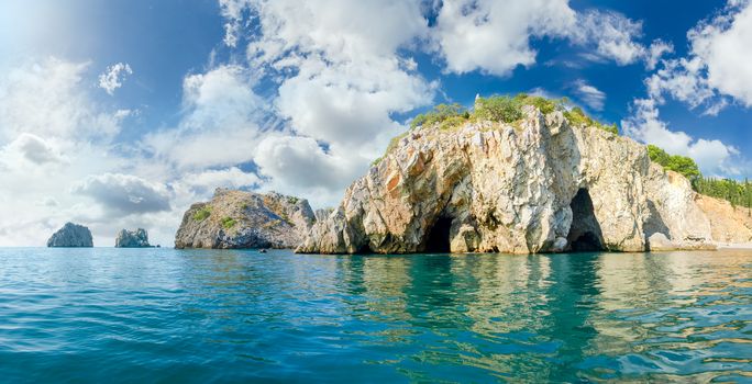 Panorama of a sea shore part with coastal cliffs with grottos on a background of the sky with clouds
