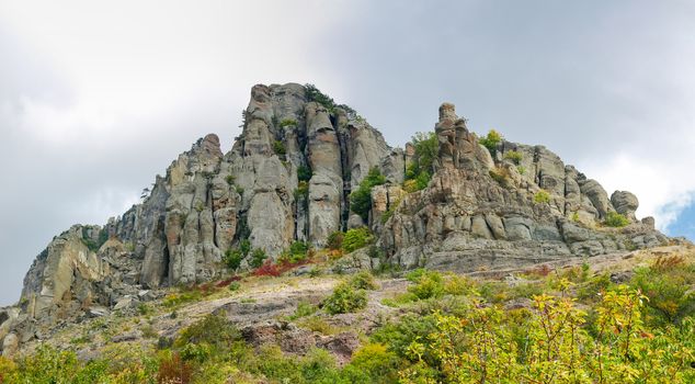 Panorama of the mountain hillside with cluster of the limestone weathered rocks with trees on a background of the sky with clouds
