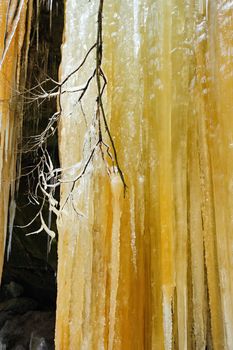 Detail frozen waterfalls on the rock, orange colored 