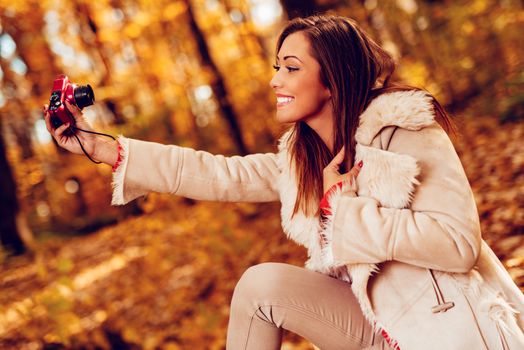 Beautiful smiling girl taking selfie in nature in autumn. 