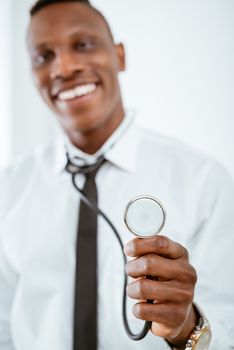 Close-up of a stethoscope in the hand of an African smiling doctor. Selective focus. Focus on foreground, on stethoscope.