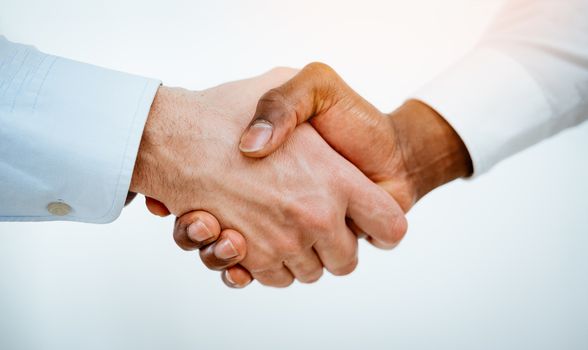 Close-up of a black and white hands shaking over a good business agreement.