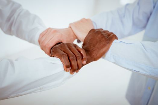 Close-up of a four black and white hands holding together tightly.