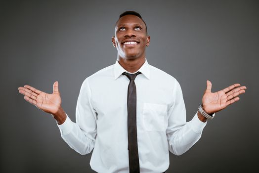 Happiness African businessman celebrating success with raised arms, looking up and praying god.