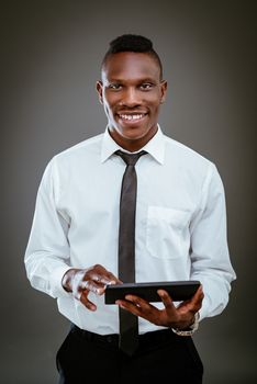 Smiling African businessman holding digital tablet and looking at camera.