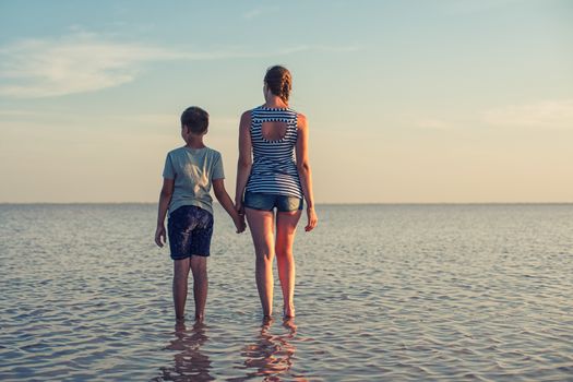 Mother and her son on salty lake with beauty sunset