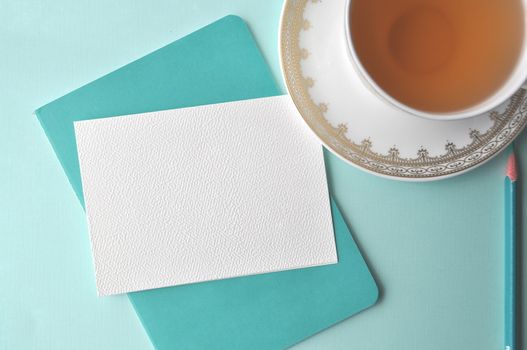 A cup of tea on aqua teal mint background with copy space on a blank note card