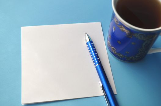 Blue porcelain cup with tea and a book on grey, white and blue background with copy space