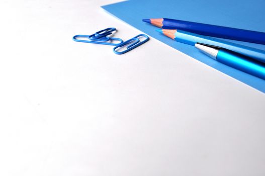 Blue pencils and a pen on white and blue background with copy space