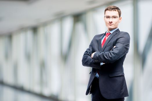 Confident manager in suit posing against in office