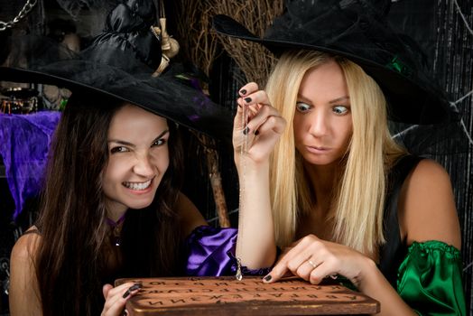 Charming young witches with a board guessing
