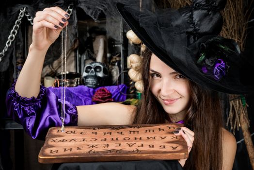 Horizontal portrait of a young cute fortune-teller in a black hat