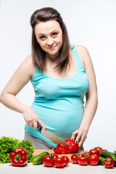 Beautiful young future mom slices a useful salad