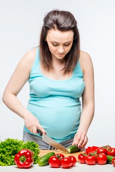 Vertical portrait of a pregnant woman while preparing a vegetable salad