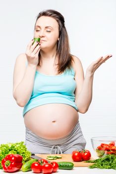 happy pregnant woman with vegetables on the table preparing a salad