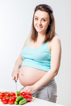 pregnant happy woman cuts fresh vegetables for lunch