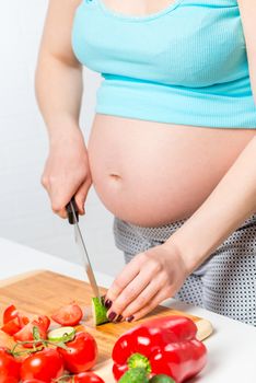 Female hands prepare vegetable salad in the kitchen, hands and stomach close-up