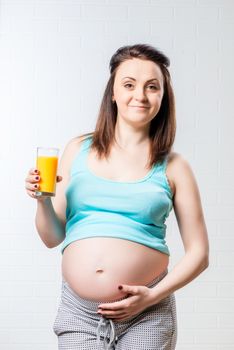 happy pregnant woman with a glass of orange juice in her hand posing