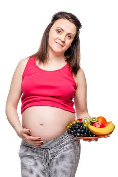 portrait of a pregnant woman with a plate of fruit on a white background isolated