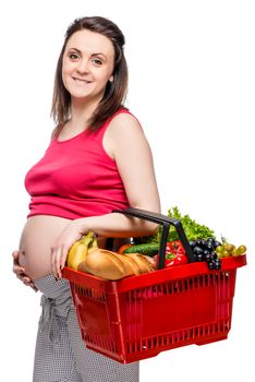 Young pregnant woman with basket of fruits and vegetables on white background isolated
