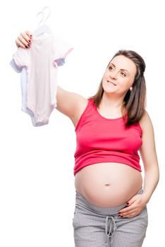 Young happy future mother chooses clothes for the kid on a white background