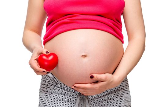 Close-up of the belly of a pregnant woman with a red heart shape - concept photo