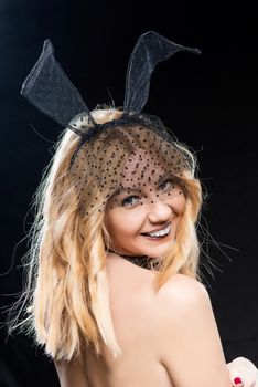 Happy temptress with hare ears on a black background