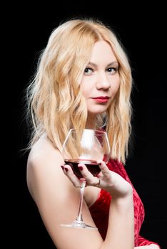 Vertical portrait of a man in a red dress with a glass of wine isolated on black