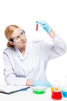 a concentrated laboratory assistant wearing glasses and gloves makes experiments with liquids in test tubes