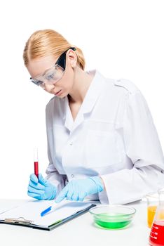 portrait of a chemist in a protective uniform at the table working with test tubes