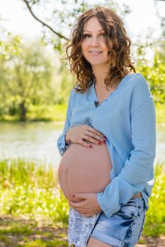 Portrait of a happy future mother in a park near the lake