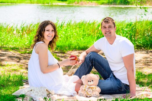 Laughing happy married couple on picnic, woman pregnant