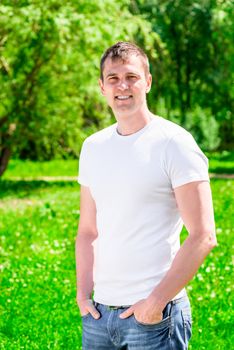 Vertical portrait of a sporty man in a summer park