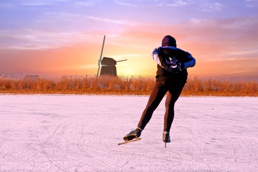 Lonely ice skater in the countryside from the Netherlands at sunset