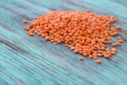 Batch of yellow lentils scattered on wooden background