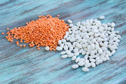 Batch of yellow lentils, white kidney haricot beans scattered on light wooden background