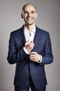 Young smiling businessman fixing cufflinks his suit.