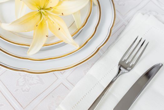 Beautifully decorated table with white plates, linen napkin, cutlery and flowers on luxurious tablecloths