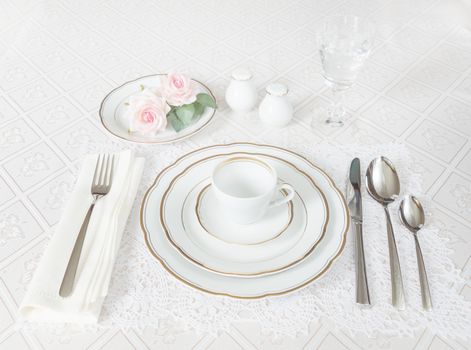 Beautifully decorated table with white plates, crystal glasses, linen napkin, cutlery and rose flowers on luxurious tablecloths