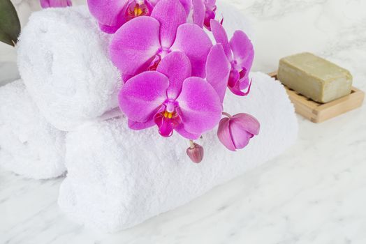 Bar of natural handmade soap, pink orchid flowers and white terry towels