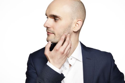 Side view of young man wearing suit. He scratches his chin.