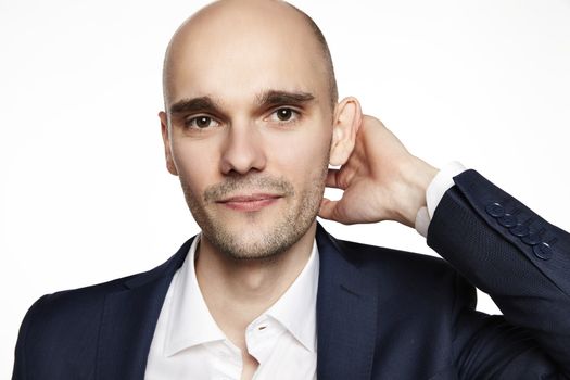 Close-up portrait of a handsome bald man stroking his head. He is smiling. White background. Horizontal.